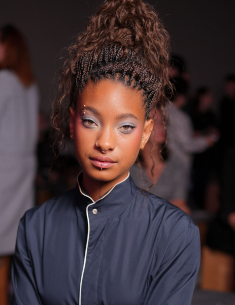 Willow Smith poses at the Dior show wearing her hair in a braided updo with wavy lengths and light blue eye shadow.